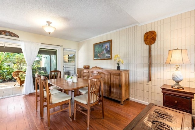 dining space with hardwood / wood-style floors and a textured ceiling