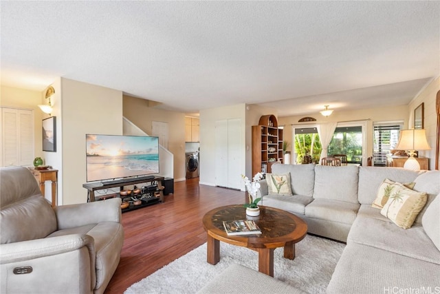 living room with washer / clothes dryer, a textured ceiling, and wood finished floors