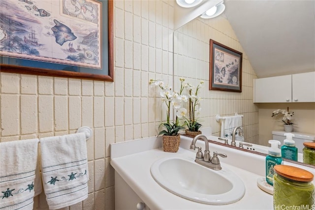 bathroom with vanity, lofted ceiling, and tile walls