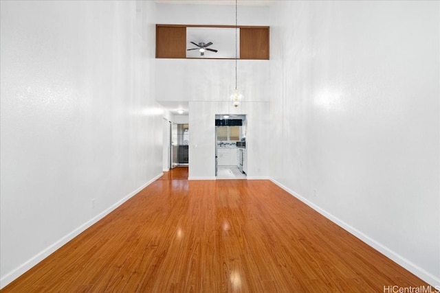 unfurnished living room with hardwood / wood-style flooring and a towering ceiling