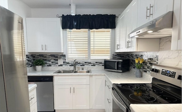 kitchen featuring sink, white cabinetry, backsplash, stainless steel appliances, and light stone countertops