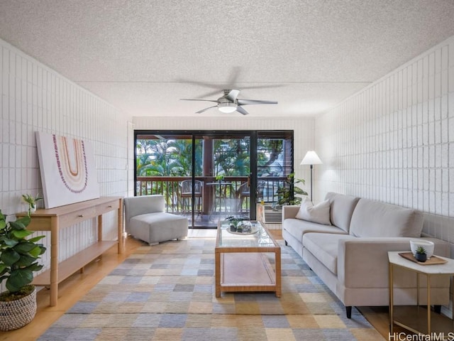 living room with ceiling fan and a textured ceiling