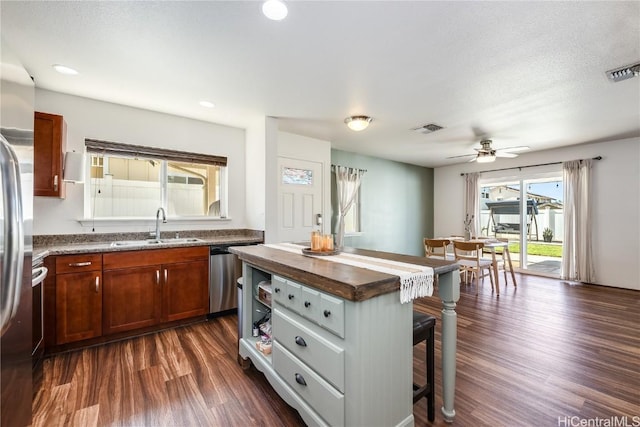 kitchen with sink, a kitchen bar, a center island, dark hardwood / wood-style floors, and stainless steel appliances