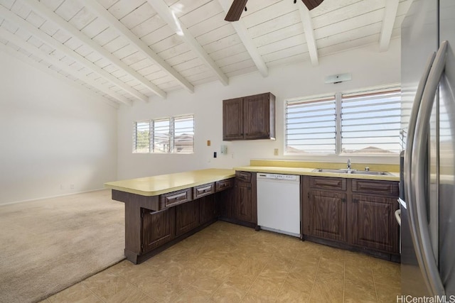 kitchen featuring sink, vaulted ceiling with beams, stainless steel fridge, kitchen peninsula, and white dishwasher