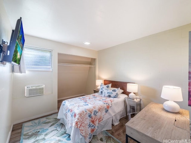 bedroom with hardwood / wood-style flooring and a wall mounted AC