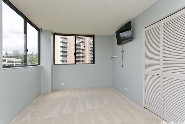 unfurnished bedroom with a closet, light colored carpet, and a textured ceiling