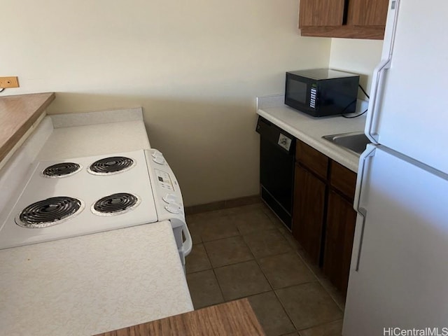 kitchen featuring dark brown cabinets, black appliances, and dark tile patterned floors