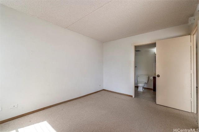 unfurnished bedroom with ensuite bath, carpet floors, and a textured ceiling