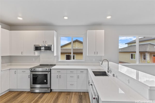 kitchen with a peninsula, stainless steel appliances, a sink, and light countertops