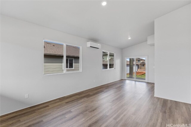 unfurnished room featuring recessed lighting, vaulted ceiling, wood finished floors, and a wall mounted AC