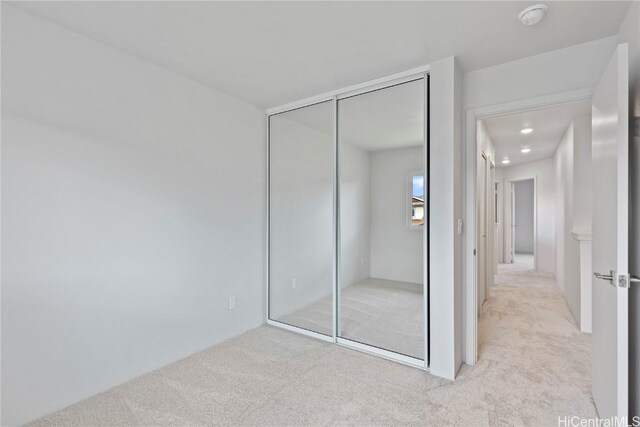 unfurnished bedroom with a closet and light carpet