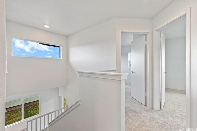 hall featuring carpet flooring and an upstairs landing