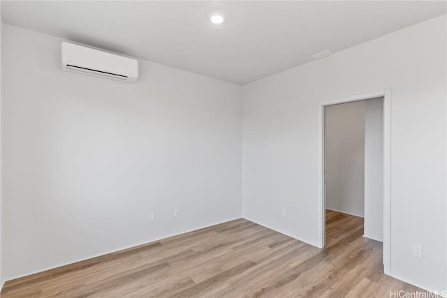 unfurnished room featuring light wood finished floors and a wall unit AC