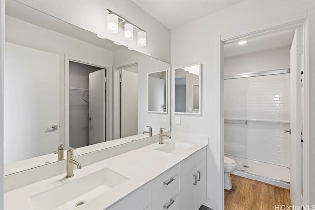 full bath featuring toilet, double vanity, a sink, and wood finished floors