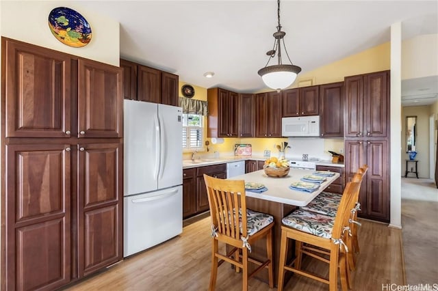 kitchen featuring sink, white appliances, a kitchen island, decorative light fixtures, and light wood-type flooring