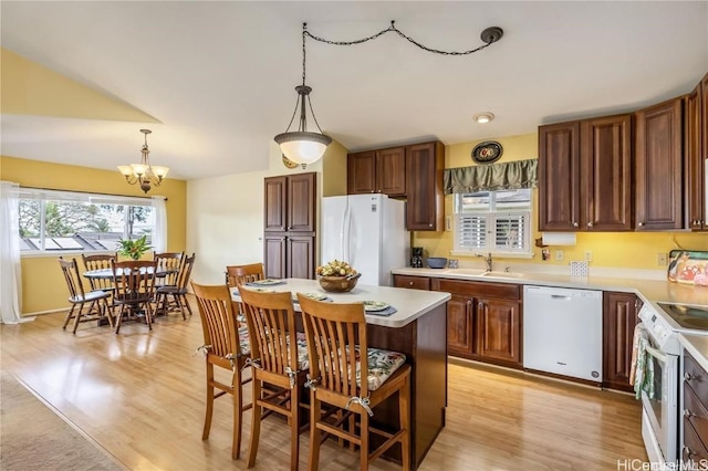 kitchen with sink, decorative light fixtures, a center island, white appliances, and light hardwood / wood-style floors