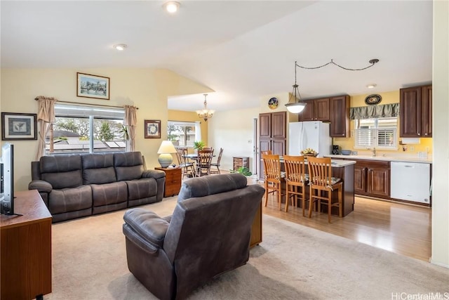 living room with a chandelier, sink, light hardwood / wood-style floors, and vaulted ceiling