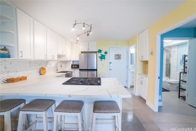 kitchen featuring a breakfast bar area, appliances with stainless steel finishes, white cabinetry, tasteful backsplash, and kitchen peninsula