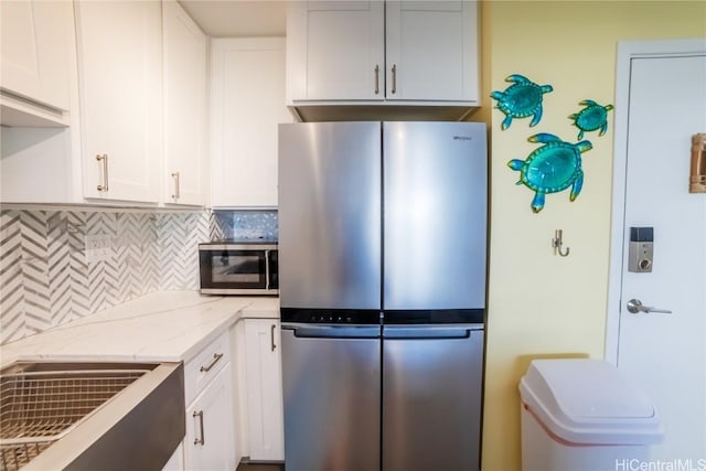 kitchen with white cabinetry, light stone counters, tasteful backsplash, and stainless steel appliances