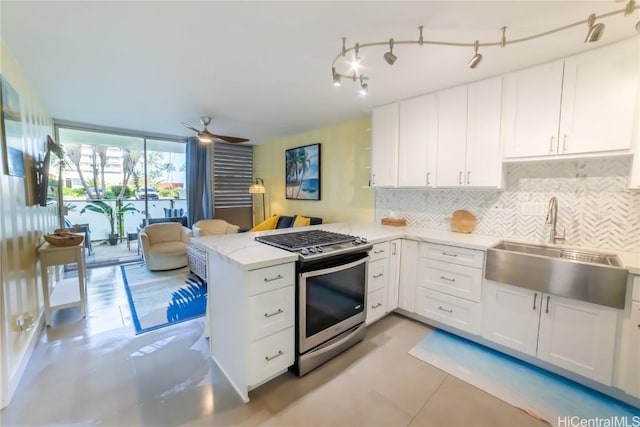 kitchen featuring sink, gas range, kitchen peninsula, white cabinets, and backsplash