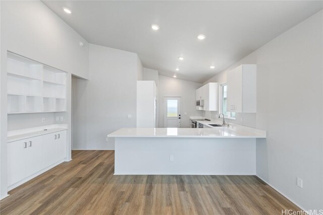 kitchen with stainless steel electric stove, white cabinetry, sink, dark hardwood / wood-style flooring, and kitchen peninsula