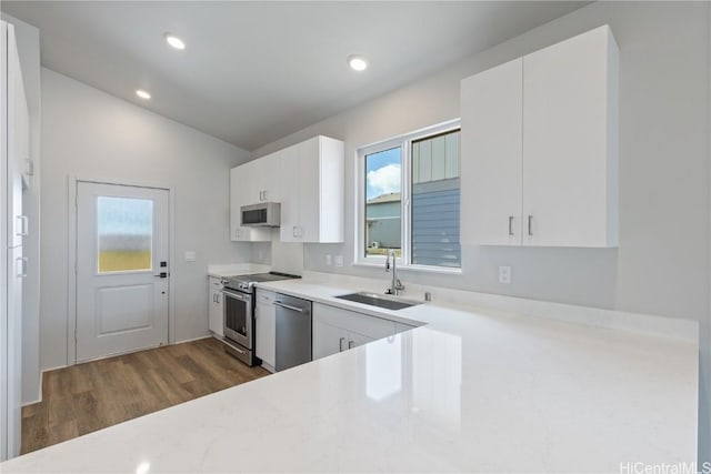 kitchen featuring lofted ceiling, sink, white cabinets, dark hardwood / wood-style flooring, and stainless steel appliances