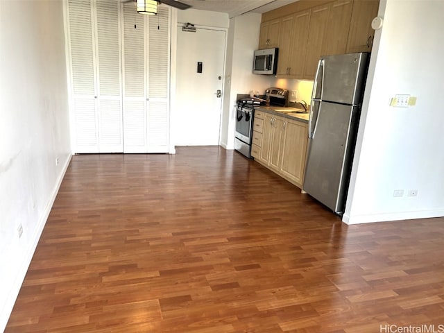 kitchen with appliances with stainless steel finishes, dark hardwood / wood-style floors, light brown cabinetry, and sink