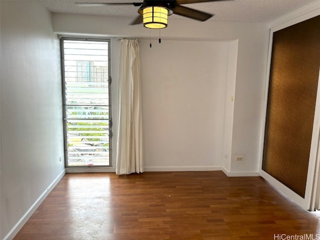 spare room featuring dark hardwood / wood-style flooring, ceiling fan, and a textured ceiling