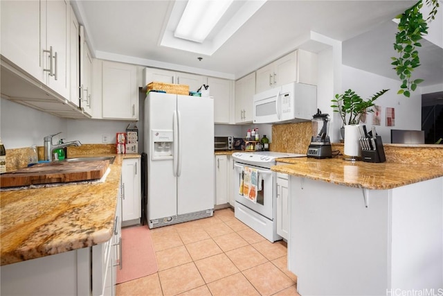 kitchen with white cabinetry, light tile patterned flooring, and white appliances