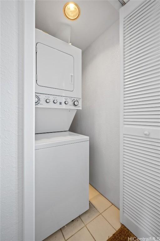 laundry area featuring stacked washer / drying machine and light tile patterned floors