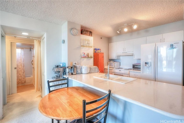 kitchen featuring kitchen peninsula, light carpet, white refrigerator with ice dispenser, white cabinetry, and a textured ceiling