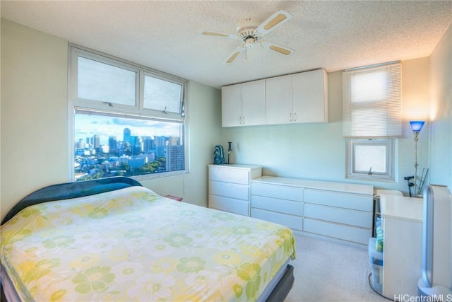 bedroom with light colored carpet, a textured ceiling, and ceiling fan