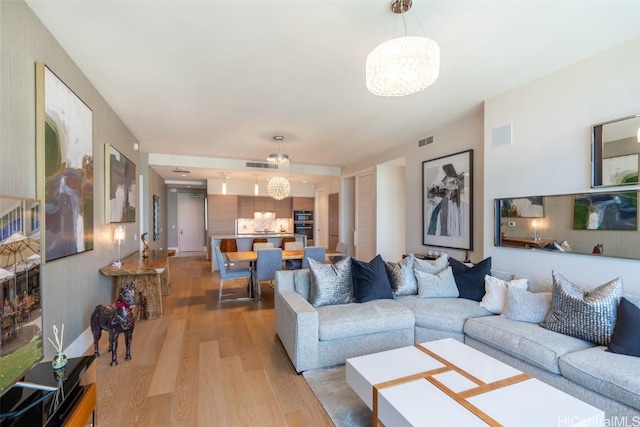 living room with an inviting chandelier and light hardwood / wood-style floors