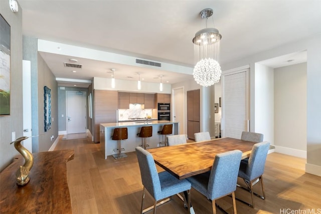 dining area with a notable chandelier and light hardwood / wood-style floors