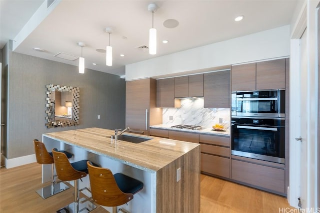 kitchen with a kitchen breakfast bar, backsplash, pendant lighting, and appliances with stainless steel finishes