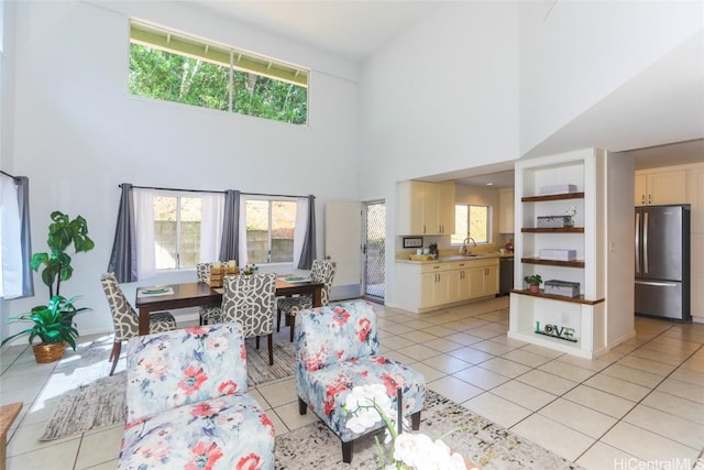 tiled living room with a high ceiling, sink, and plenty of natural light