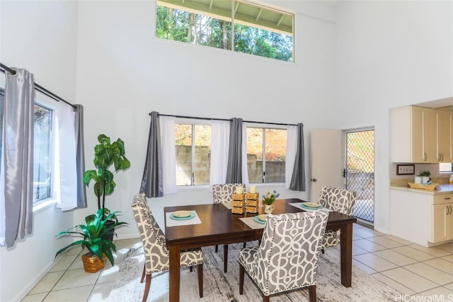 dining space featuring a high ceiling, light tile patterned floors, and a healthy amount of sunlight