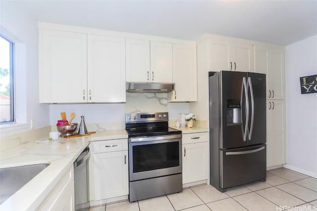 kitchen with light stone countertops, white cabinets, stainless steel appliances, sink, and light tile patterned floors