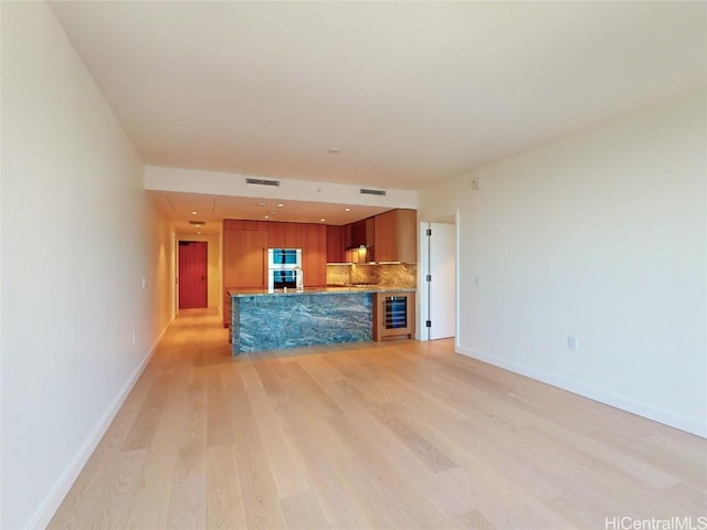 unfurnished living room featuring light hardwood / wood-style flooring and beverage cooler