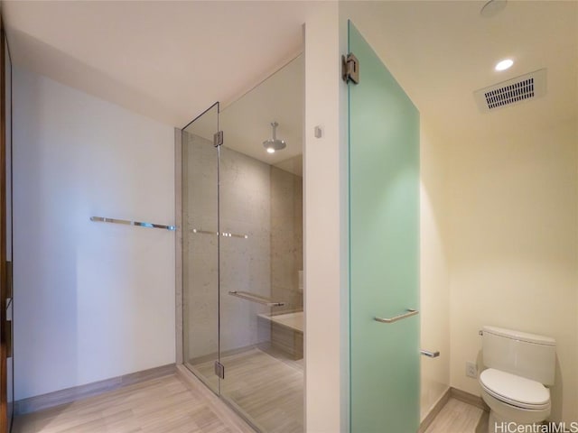 bathroom featuring wood-type flooring, toilet, and an enclosed shower