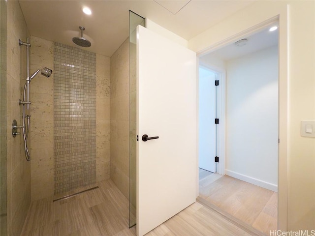 bathroom featuring hardwood / wood-style flooring and a tile shower