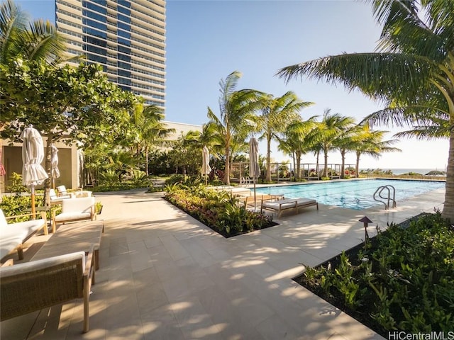 view of pool with a water view and a patio