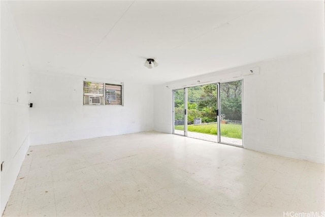 spare room with concrete block wall, cooling unit, and tile patterned floors