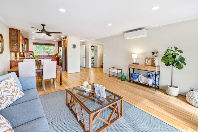 living room with sink, ceiling fan, a wall mounted AC, and light hardwood / wood-style flooring