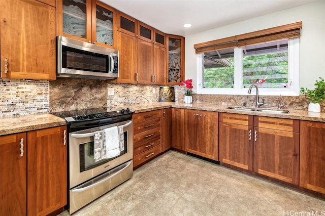 kitchen featuring sink, backsplash, light stone counters, and appliances with stainless steel finishes