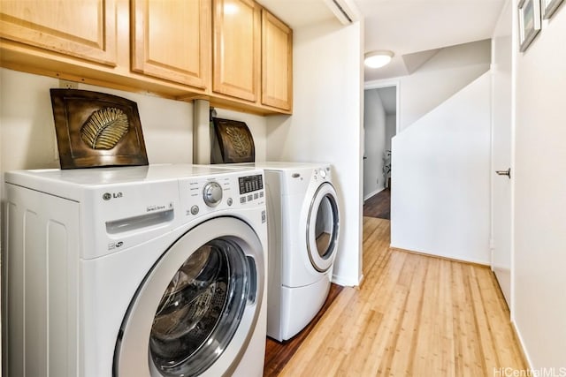 laundry area with cabinets, light wood-type flooring, and washer and clothes dryer