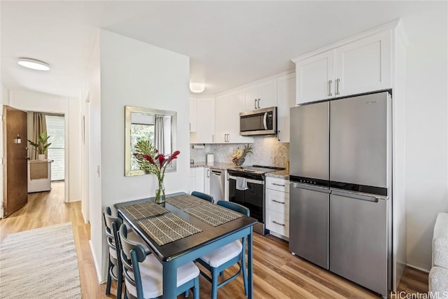 kitchen with white cabinetry, light hardwood / wood-style flooring, tasteful backsplash, and appliances with stainless steel finishes