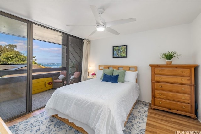 bedroom featuring access to outside, light hardwood / wood-style floors, floor to ceiling windows, and ceiling fan