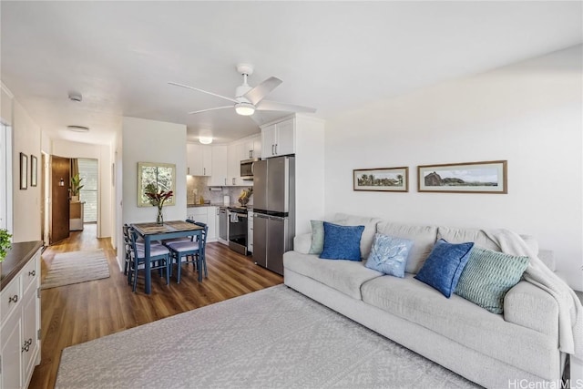 living room featuring ceiling fan and dark hardwood / wood-style flooring