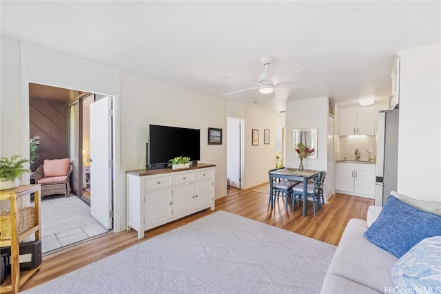 living room featuring ceiling fan, sink, and light hardwood / wood-style floors